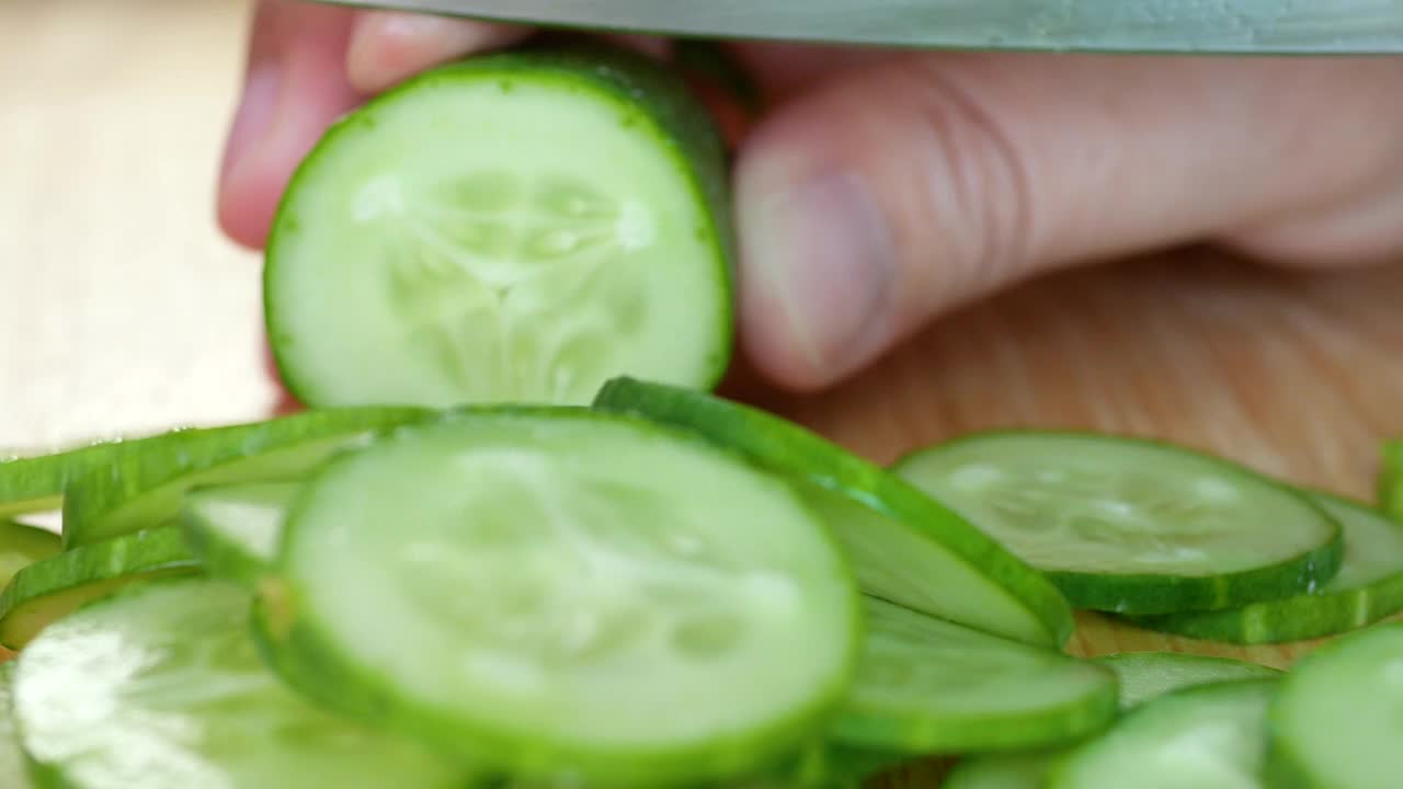 女人在厨房准备食物的木板上切绿色新鲜黄瓜的特写视频素材