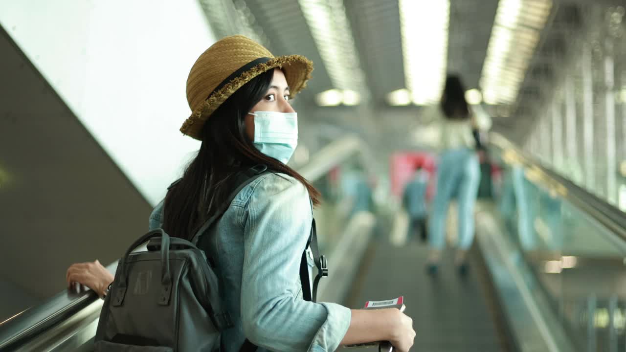 一个漫不经心的年轻女子在候机楼的门口走着。年轻妇女独自乘飞机旅行视频素材