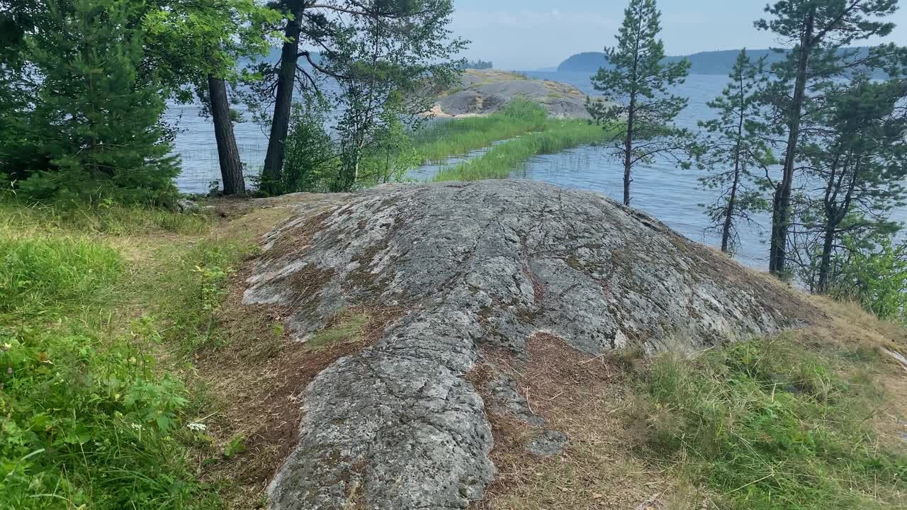 湖岸由巨大的灰色石头和冷杉和海藻组成，通向岛上的一块巨石视频素材