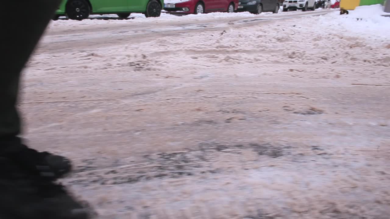 行人的脚踏着冬天的鞋在雪地上行走，行人滑的路视频素材