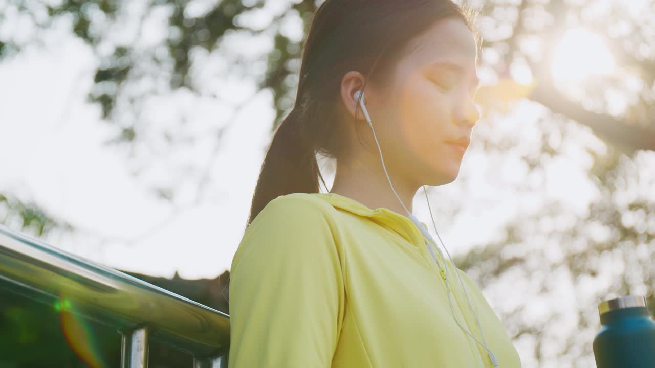 一位美丽的白人女运动员在公园跑步后喝水。女性从运动中休息，慢跑。视频素材