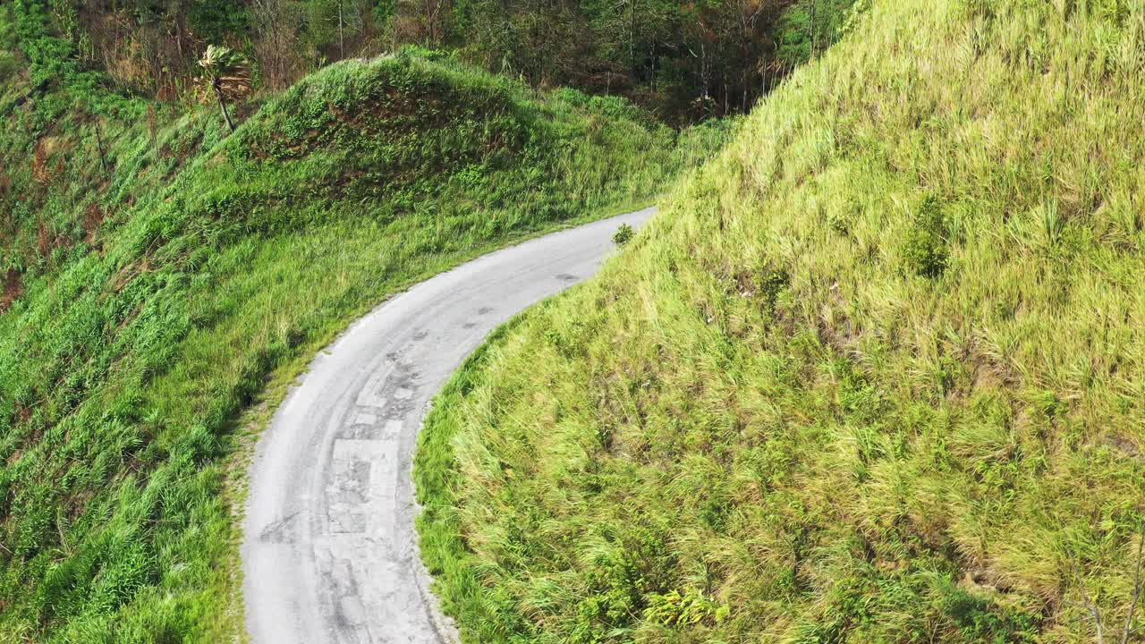 高山上铺砌的道路的鸟瞰图，从远处可以看到错综复杂的绿色山脉，4k视频素材