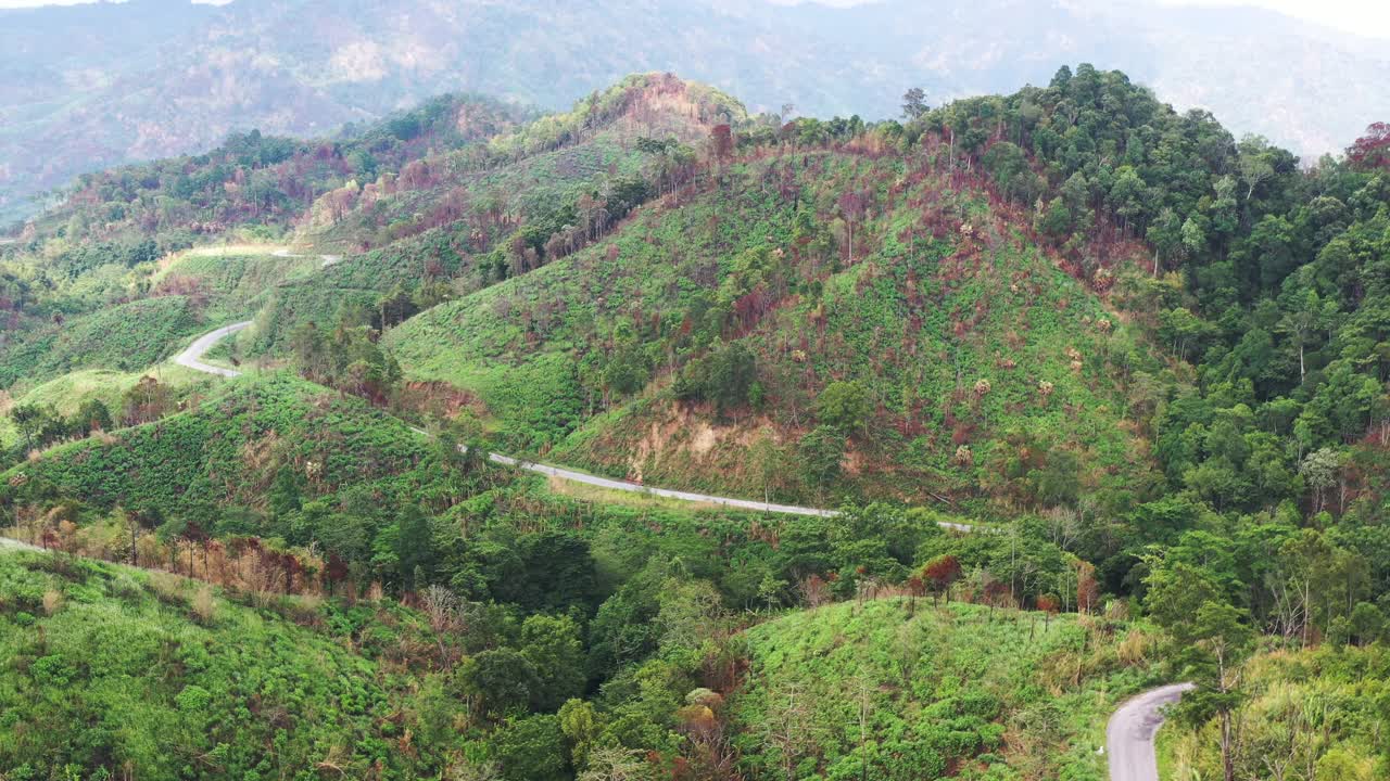 高山上铺砌的道路的鸟瞰图，从远处可以看到错综复杂的绿色山脉，4k视频素材