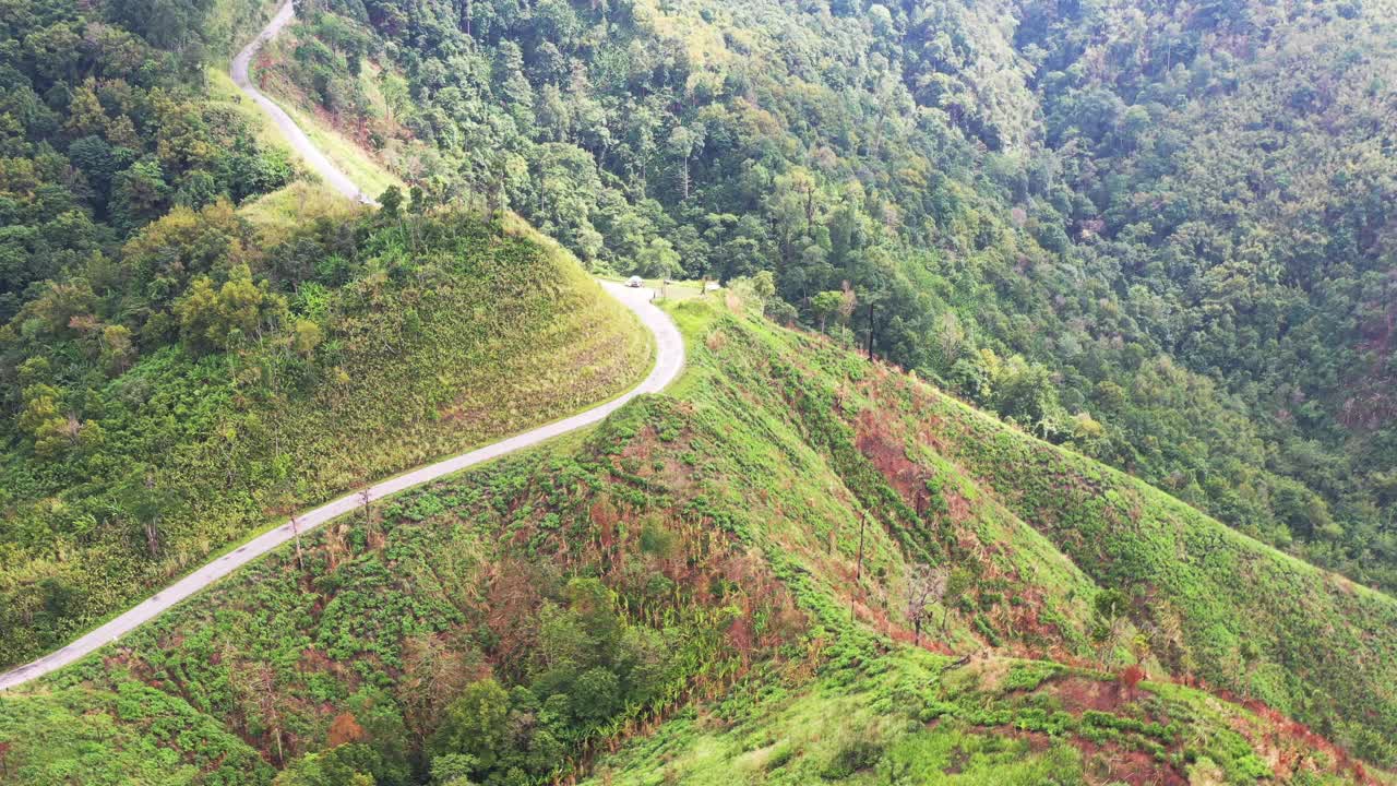 高山上铺砌的道路的鸟瞰图，从远处可以看到错综复杂的绿色山脉，4k视频素材