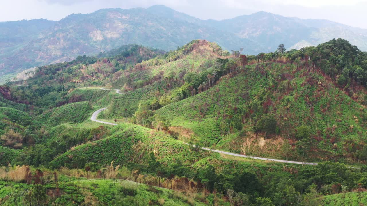 高山上铺砌的道路的鸟瞰图，从远处可以看到错综复杂的绿色山脉，4k视频素材