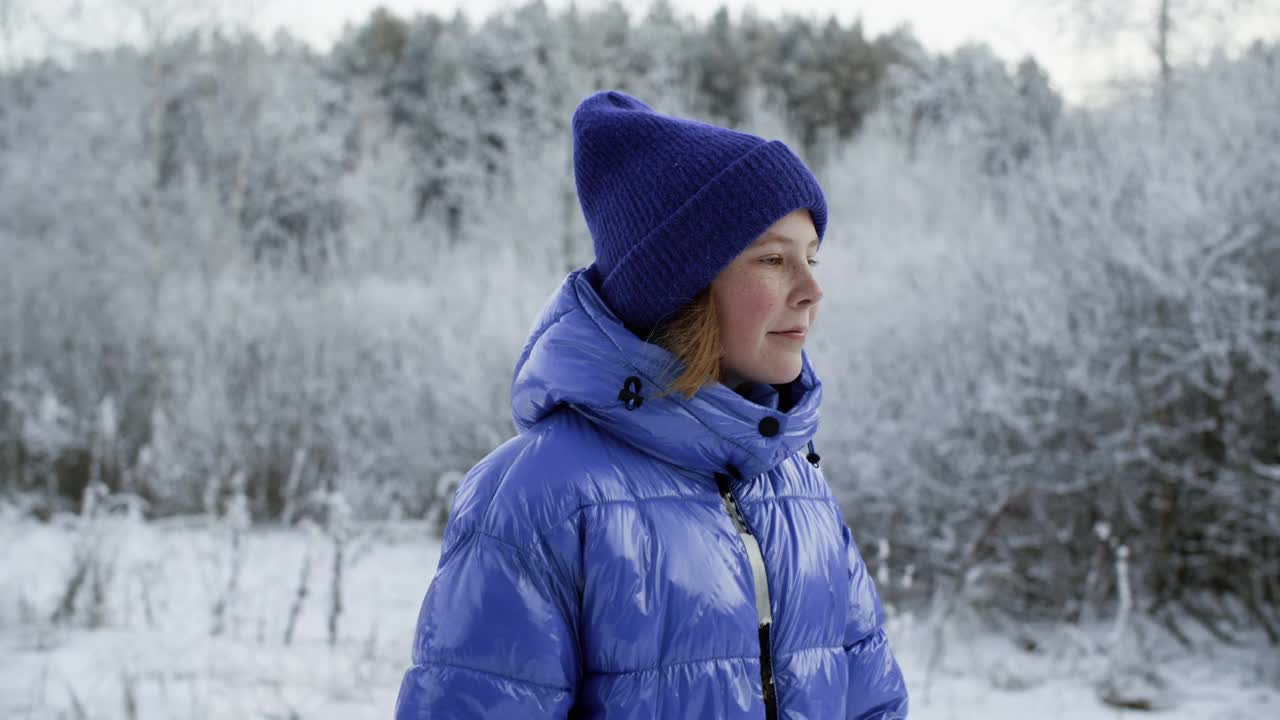 可爱的女孩在雪地里漫步。肖像美丽的少女在编织的帽子和蓝色夹克在冬天的森林。视频素材