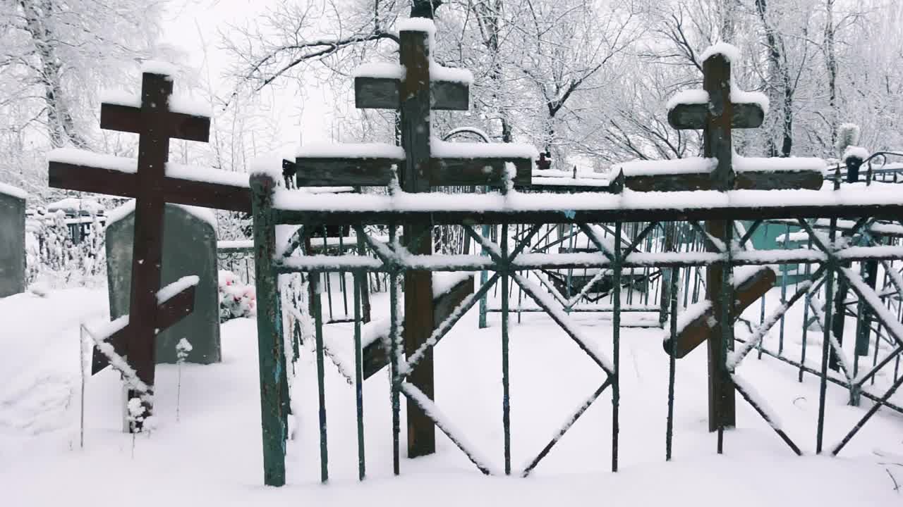 在飘落的雪花中，木制的十字架和栅栏缓缓地映入眼帘视频素材