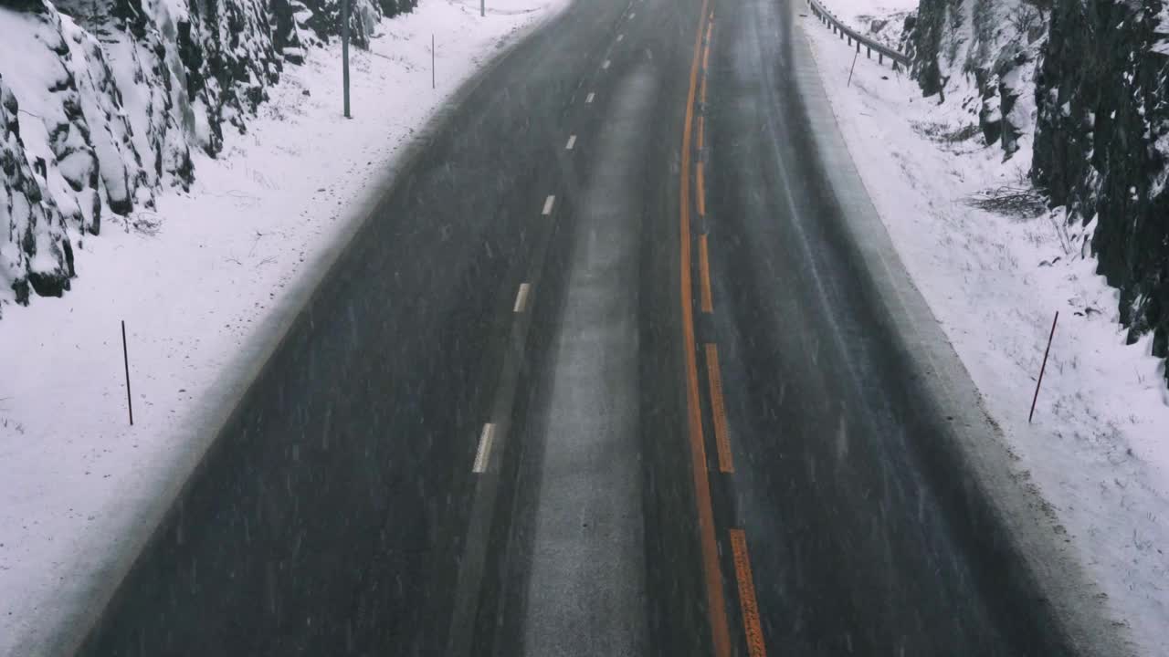 在一个寒冷的冬天，一条没有交通的高速公路上下雪了。沥青加路面盐，使道路不受冰雪的影响。视频素材