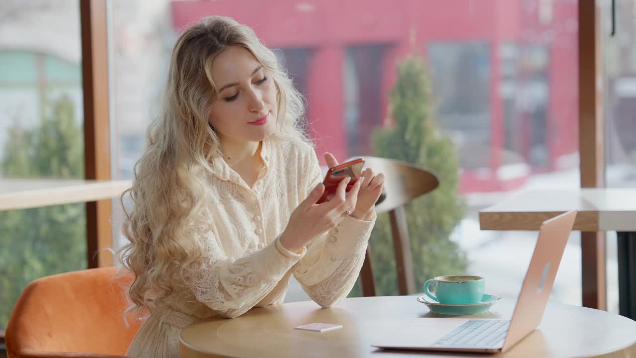 优雅苗条美丽的女人坐在咖啡馆用智能手机上网。微笑的美丽的白人女士在室内咖啡馆休息的肖像。休闲的生活方式。视频素材