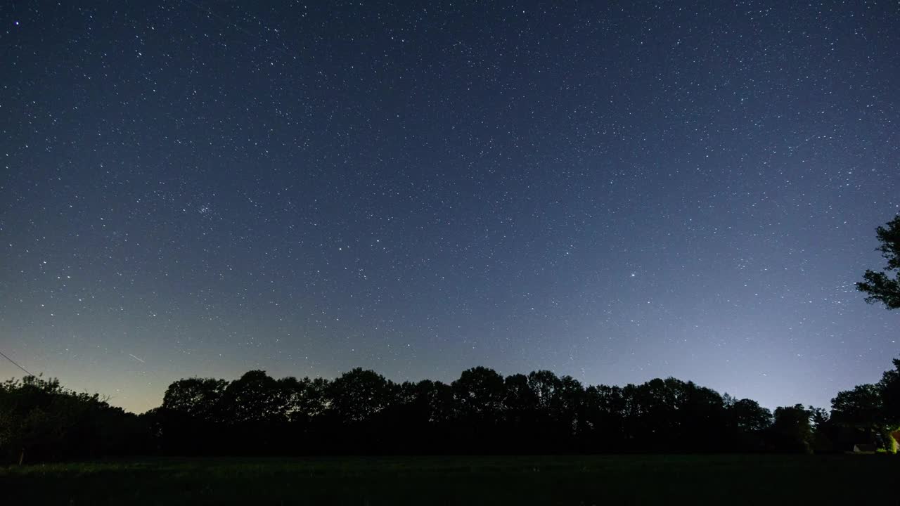 移动的星空与星星的轨迹在乡村景观与田野在树前视频素材