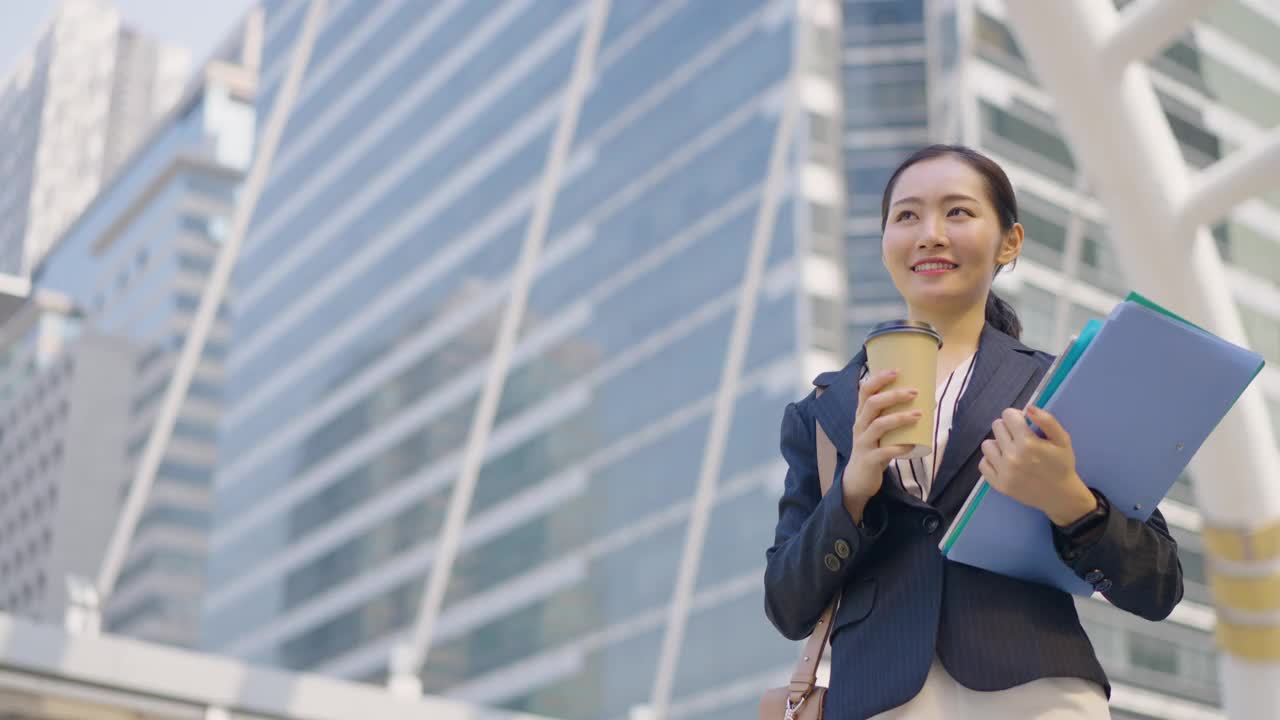 自信的年轻女商人一边喝咖啡一边在城市里散步视频素材