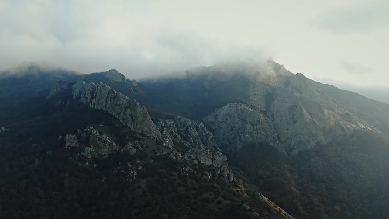 鸟瞰图。飞到山顶上有云，山坡上长满了罕见的树木。视频素材