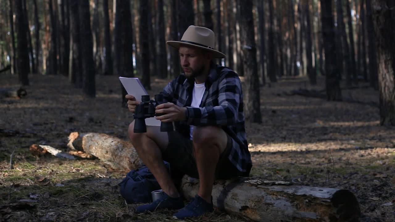 年轻人在山上或森林里徒步旅行时，一边休息一边查地图视频下载