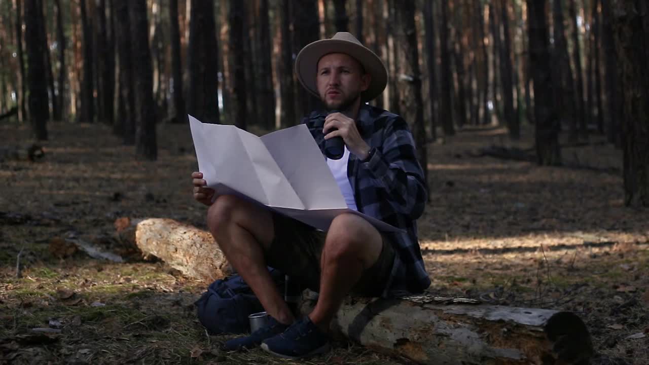 年轻人在山上或森林里徒步旅行时，一边休息一边查地图视频素材