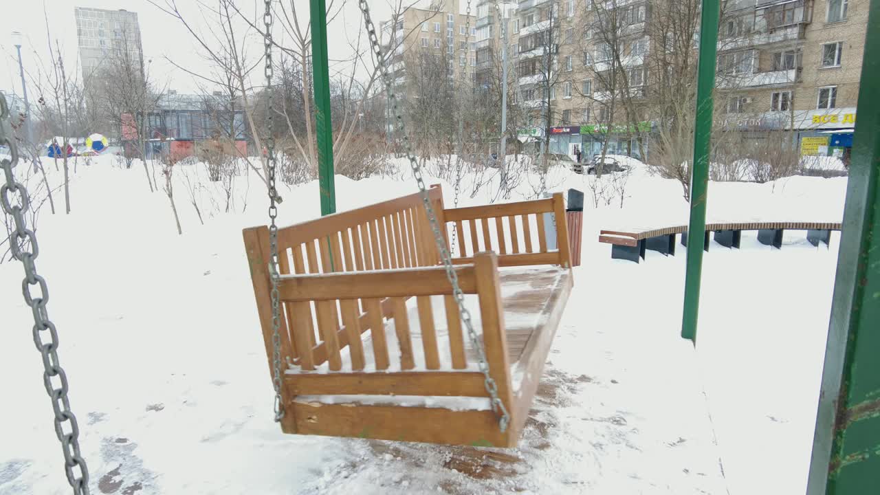 空荡的木制秋千长椅在冬天的时间里有雪。视频素材