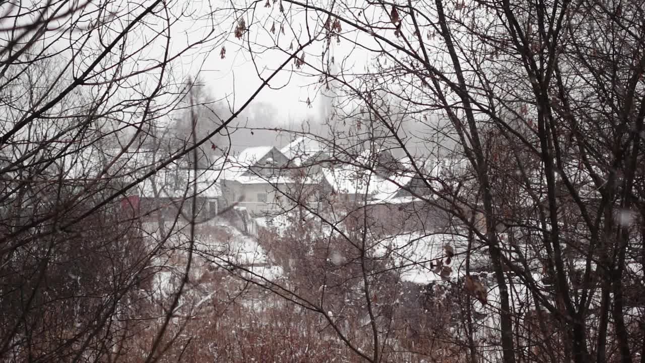 在冬日里，透过树枝以慢镜头拍摄乡村的房屋景观视频素材