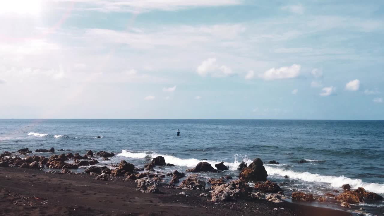 自然宁静的海滩风景与大块的海洋岩石和渔民捕鱼在Umeanyar村视频素材