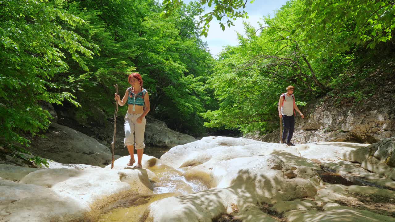 一群游客沿着一条清澈的山河走在峡谷底部。视频素材