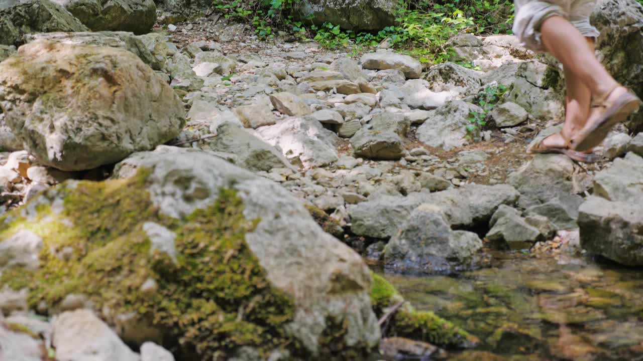 年轻的女游客沿着峡谷底部的绿色森林和清澈的山河行走。视频素材