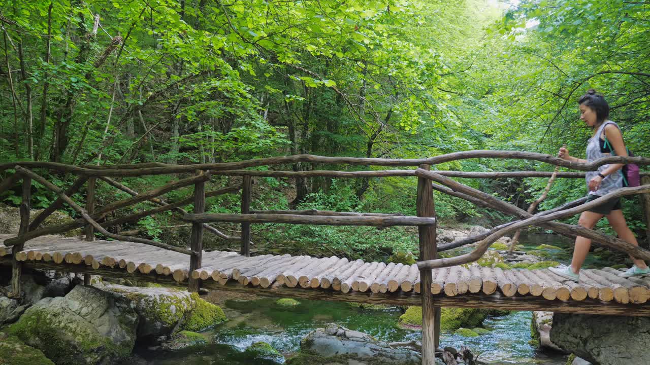 一群游客走过一座桥，桥上有清澈的河水。视频素材