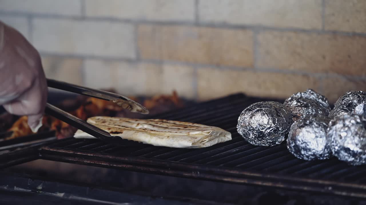 在热烤架上烹饪的美味食物。专业厨师正在准备皮塔饼，然后把它翻过来放在炉子上熏制。视频素材