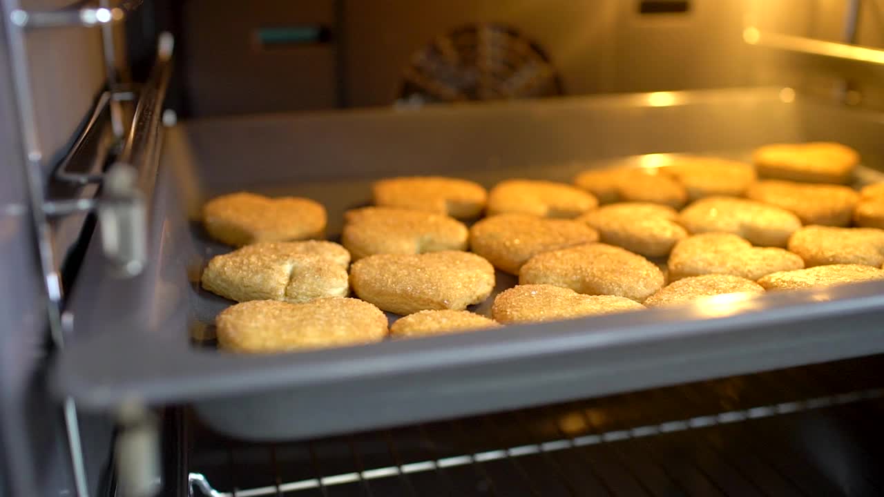 从烤箱里拿出饼干。手工制作的晚餐。家里做的甜点。快乐的家庭烹饪，手从烤箱里拿出饼干。烘烤的过程。慢动作视频素材