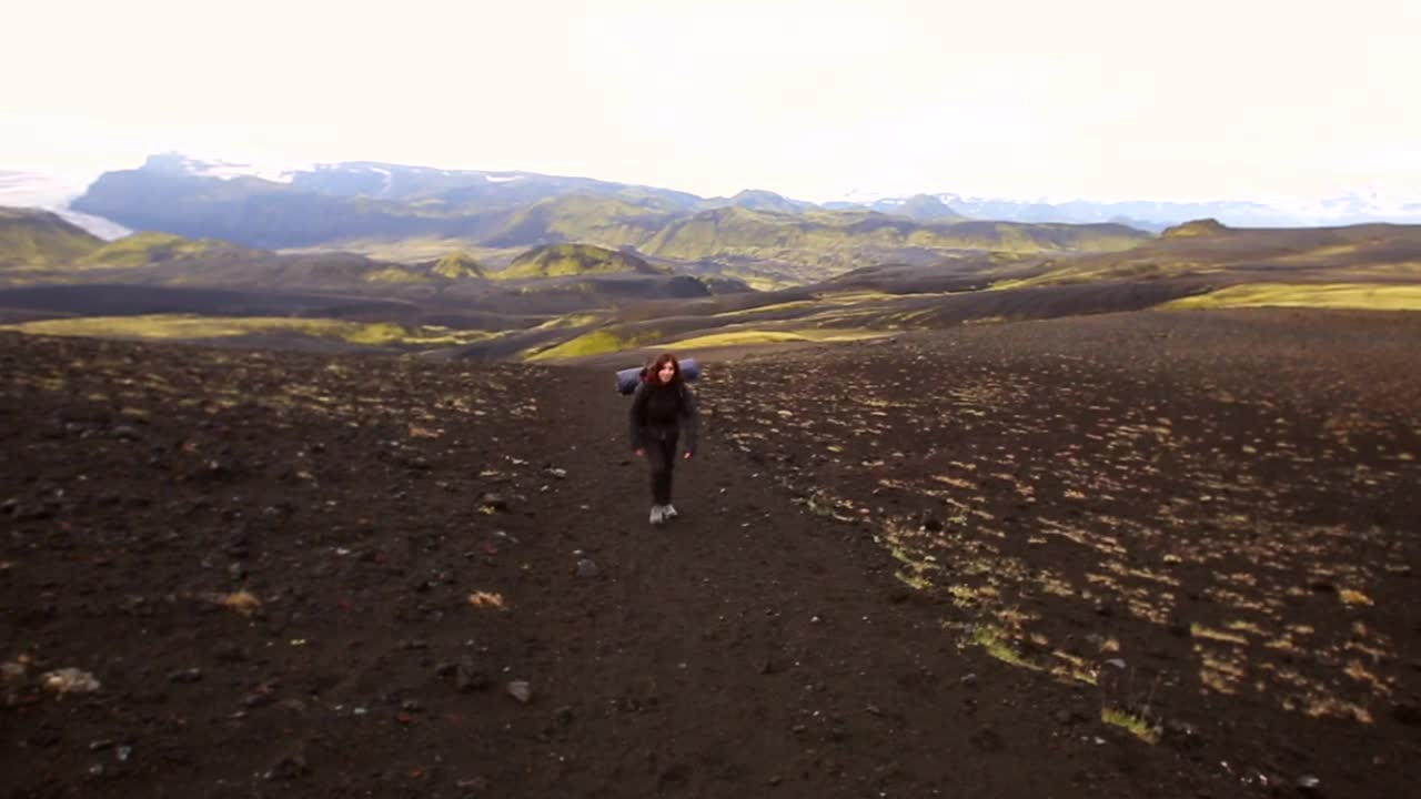 一个年轻的女孩站在美丽的绿色山上，从Landmannalaugar，冰岛54公里的长途跋涉视频素材