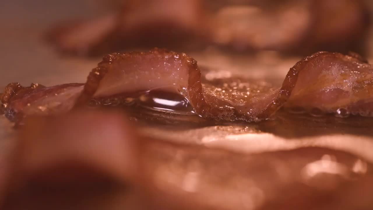 在煎锅里煎培根片特写。脂肪或油会沸腾并起泡。家庭烹饪的概念视频素材