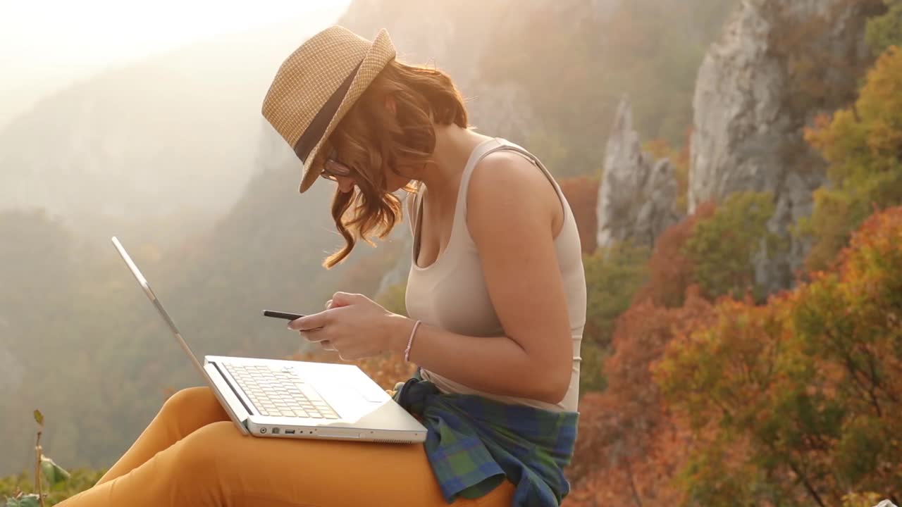 女人喜欢在山上。一位年轻美丽的女子在山顶享受自然，并在她的视频博客上工作。视频素材