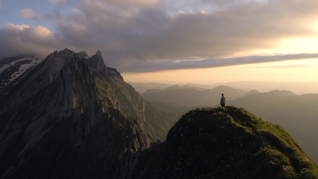 年轻人高举双手站在山顶上。视频素材