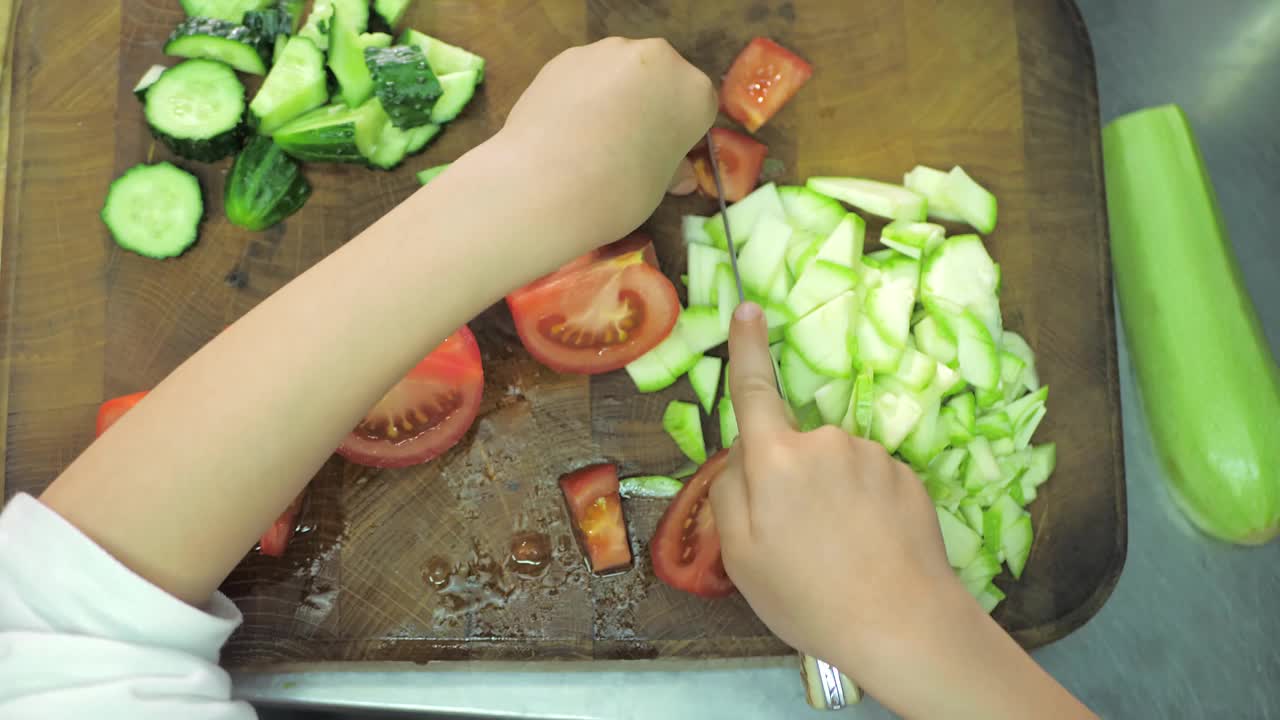 健康饮食。孩子们在餐厅厨房切蔬菜沙拉视频素材