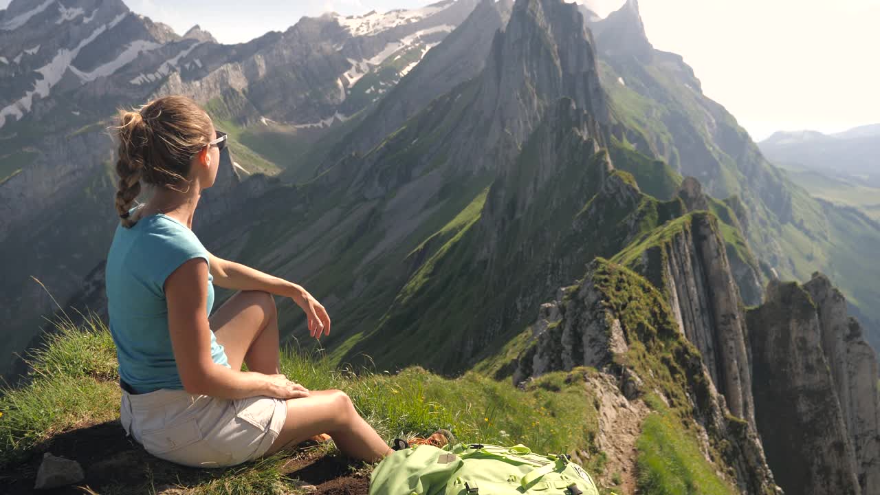 年轻女子在徒步旅行中凝视着令人惊叹的山脉景色。手臂张开视频素材