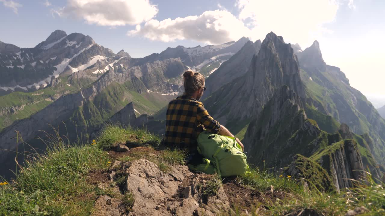 一个徒步旅行的年轻人凝视着令人惊叹的山脉景色。手臂张开视频素材