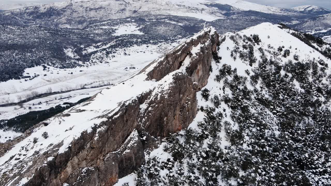 在白雪覆盖的山的悬崖上史诗般的飞行。高质量4k镜头视频素材