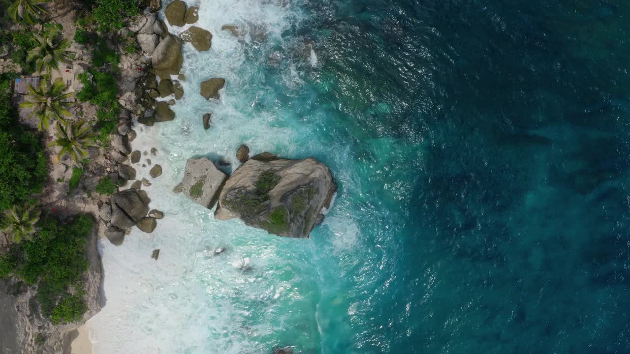 无人机接近海滩的鸟瞰图与长满植被的巨石视频素材