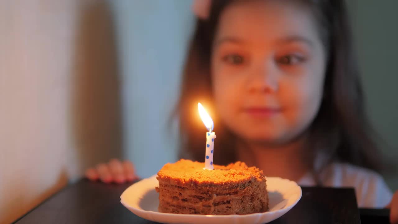 可爱的小女孩吹灭生日蛋糕上的蜡烛视频素材