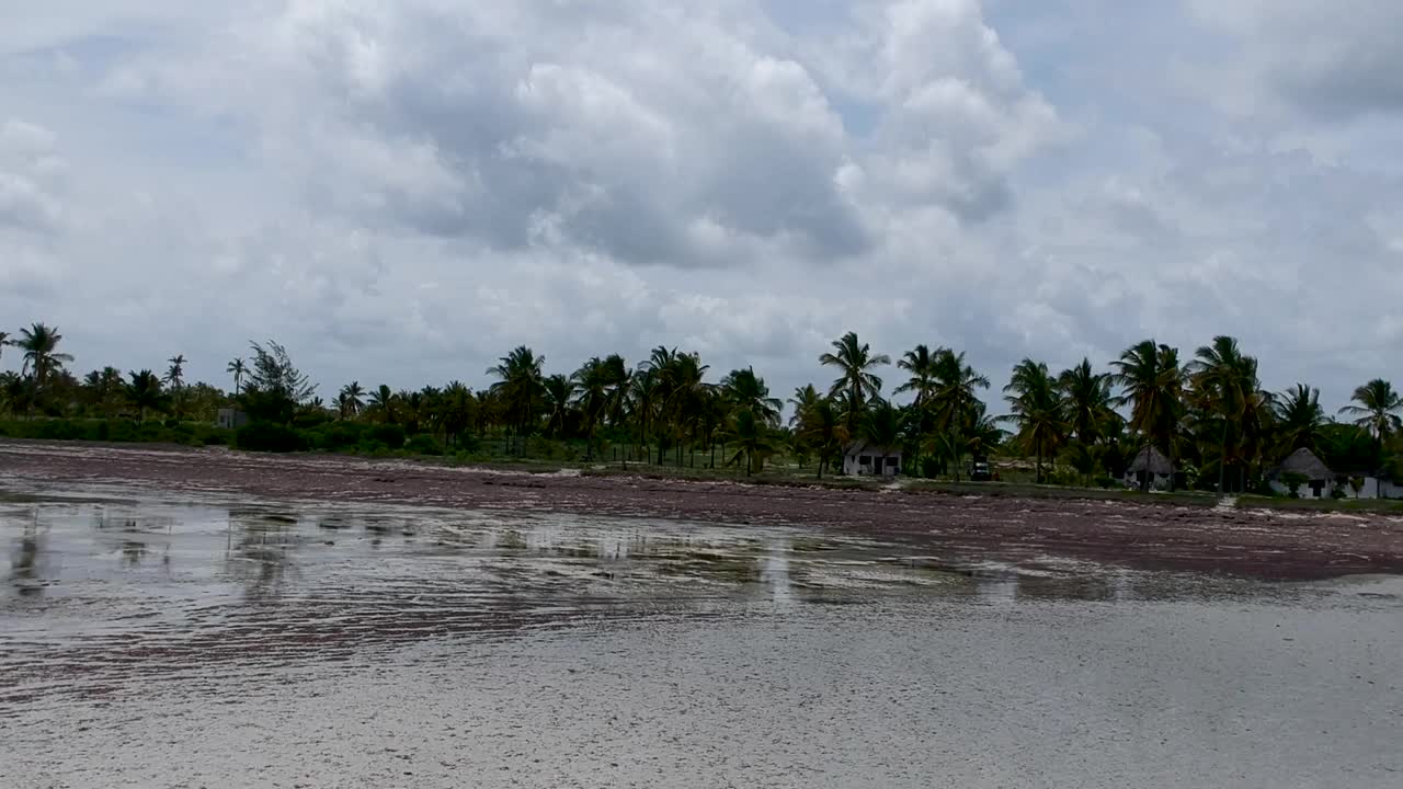 热带白色海滩与棕榈树反射在浅水的海水下的海滩度假白色小屋下棕榈树航拍视频。视频素材