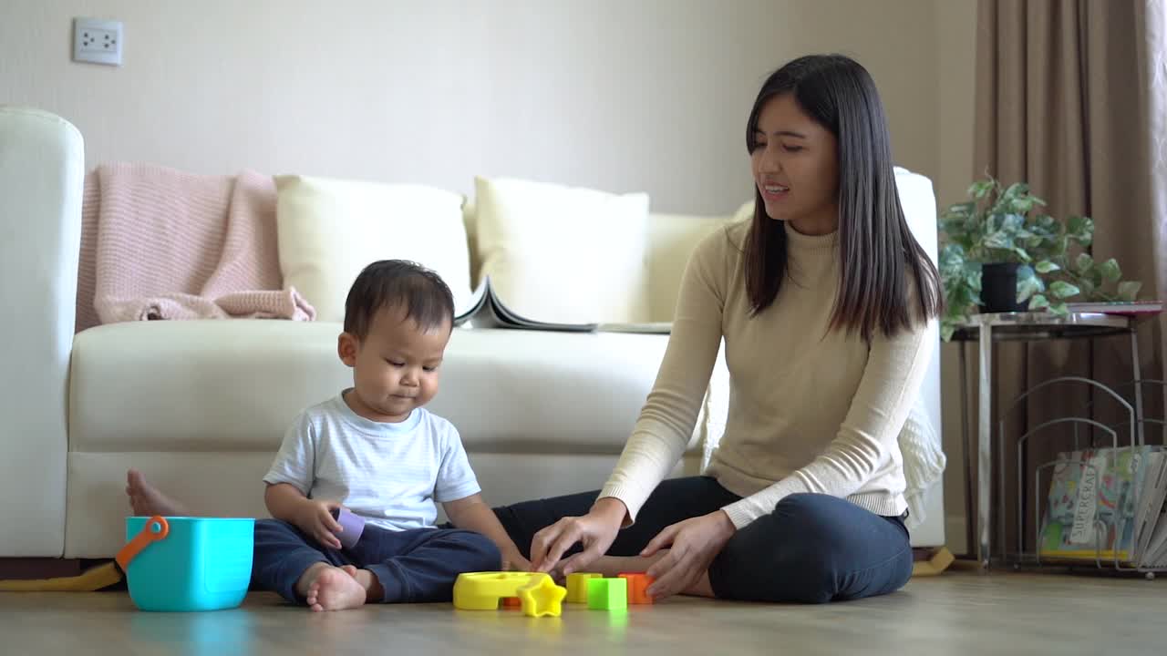 年轻的母亲和小男孩在家里沙发附近的地板上玩耍。幸福的家庭。视频素材