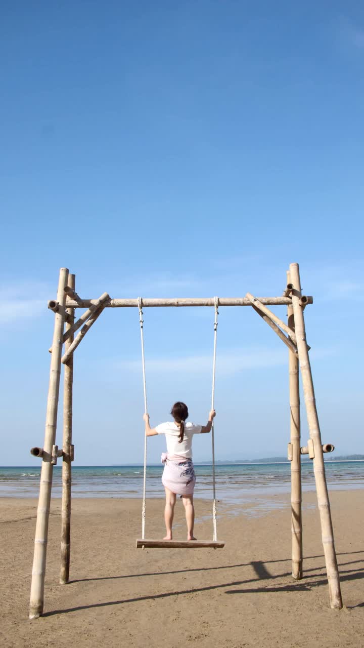 年轻女子游客放松在热带海滩上的秋千视频素材