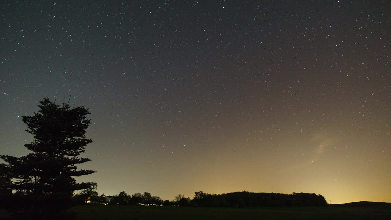 移动的夜空在乡村景观与田野前的森林剪影视频素材