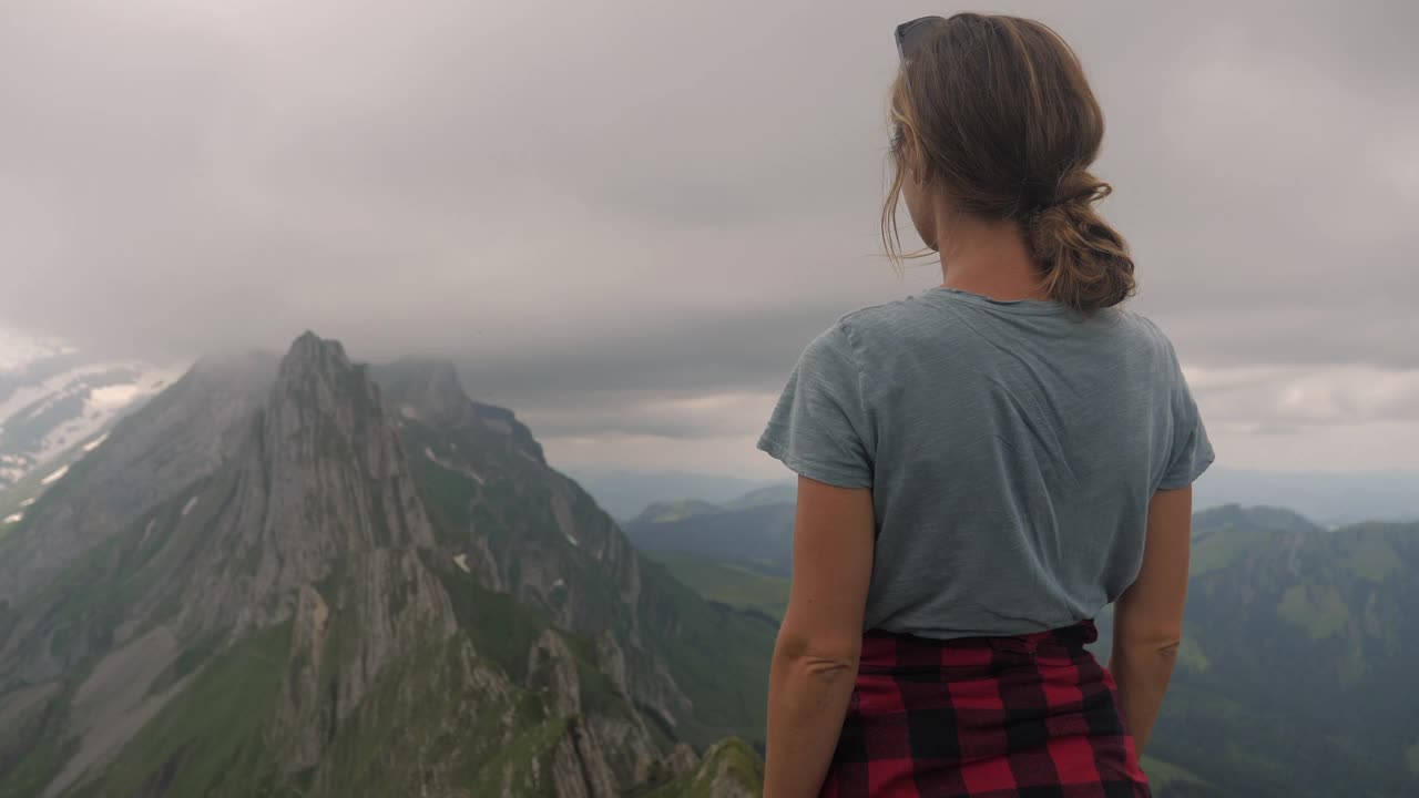 女人在一个徒步旅行看壮观的山景观双臂张开视频素材