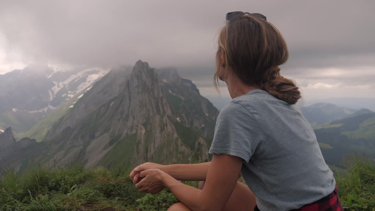 年轻女子在徒步旅行中凝视着令人惊叹的山脉景色视频素材