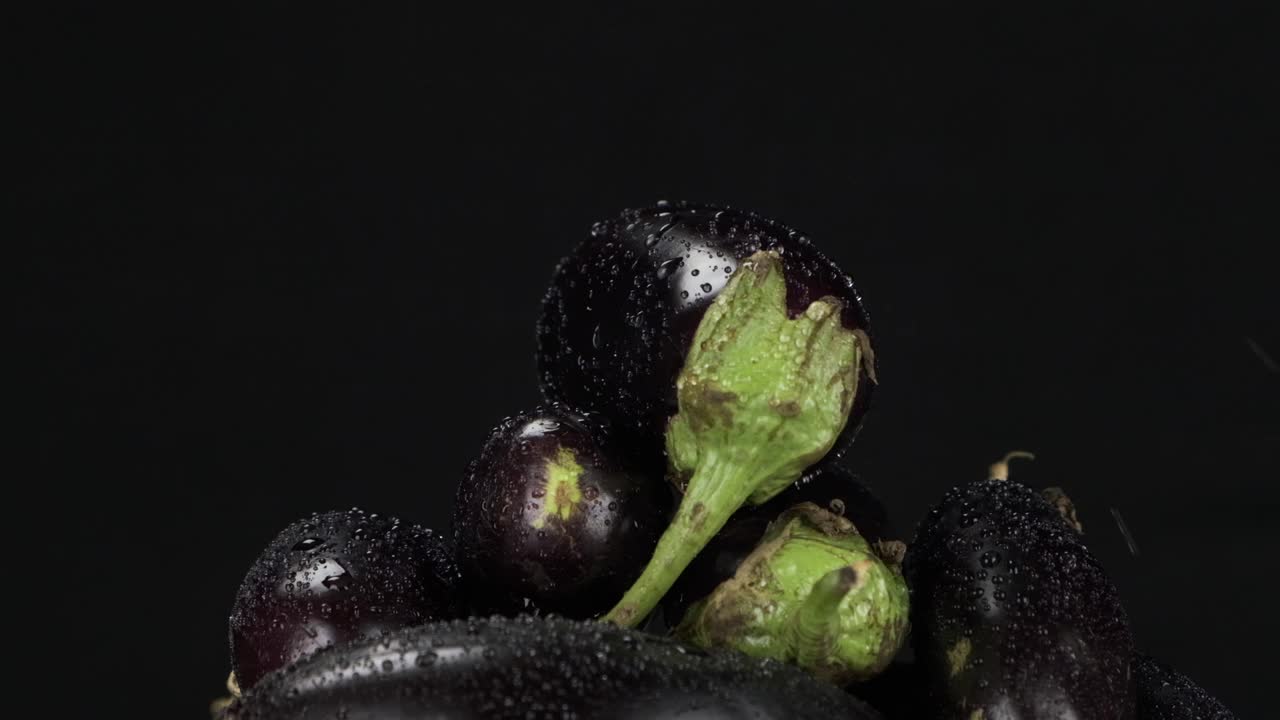 缓慢的运动。雨滴落在一堆旋转的紫色茄子上。视频素材