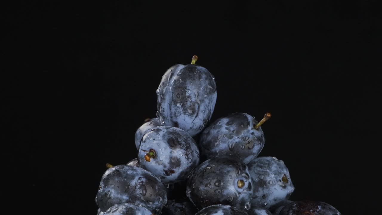 缓慢的运动。雨滴落在一堆旋转的李子上。视频素材