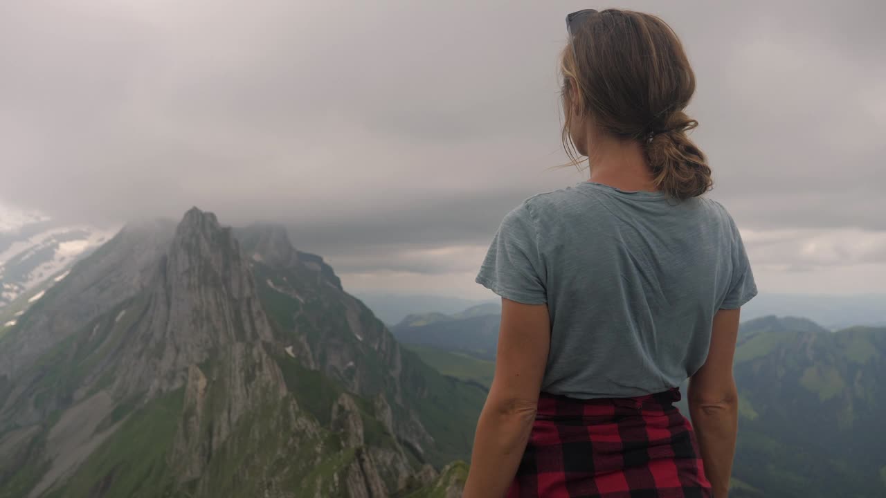 慢镜头:徒步旅行的女子张开双臂看着壮观的山景视频素材