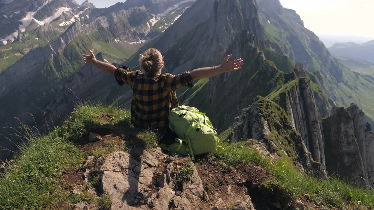 慢镜头:徒步旅行的年轻人凝视着令人惊叹的山景。手臂张开视频素材