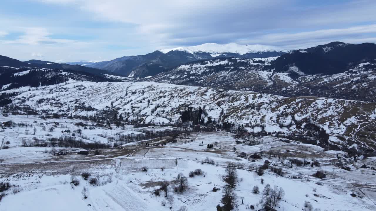 从无人机到冰雪覆盖的喀尔巴阡山脉和村庄的景观。视频素材