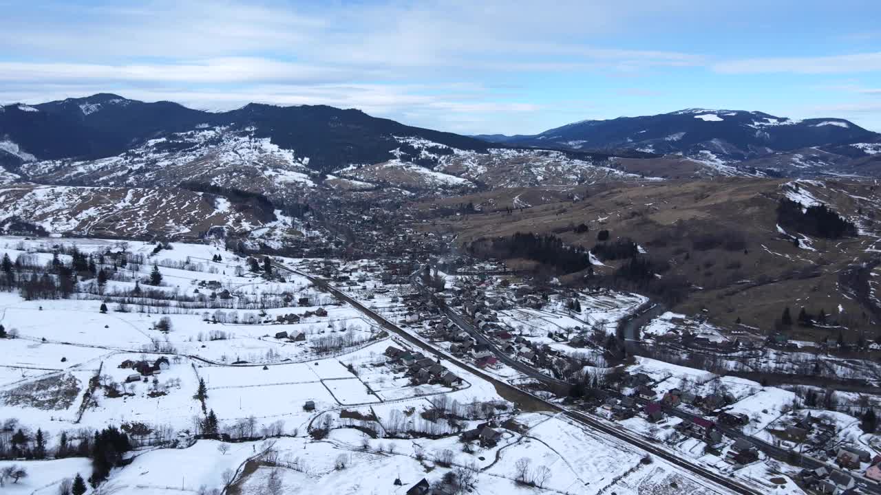 从无人机到冰雪覆盖的喀尔巴阡山脉和村庄的景观。视频素材