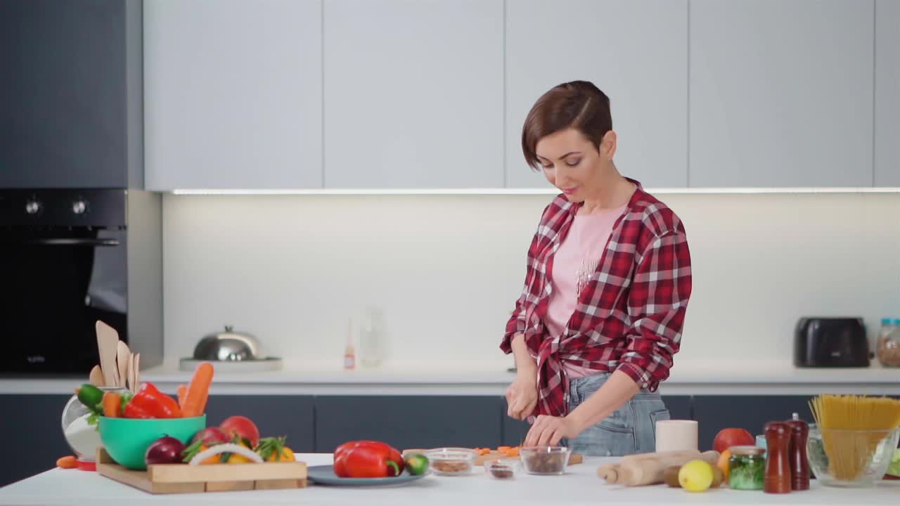 在她的新家做饭快乐的女人。在餐桌上准备食材的年轻女子正在厨房里做午餐。健康的食物生活。健康的生活方式。新屋的概念视频素材