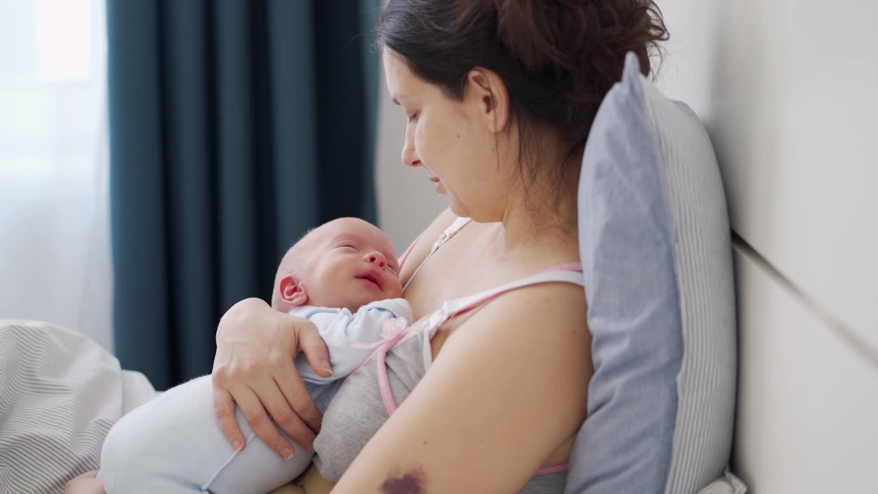 妈妈抱着刚出生的婴儿，妈妈和她3周大的小男孩躺在床上视频素材